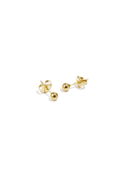 Pair of shiny gold dot stud earrings displayed on white surface