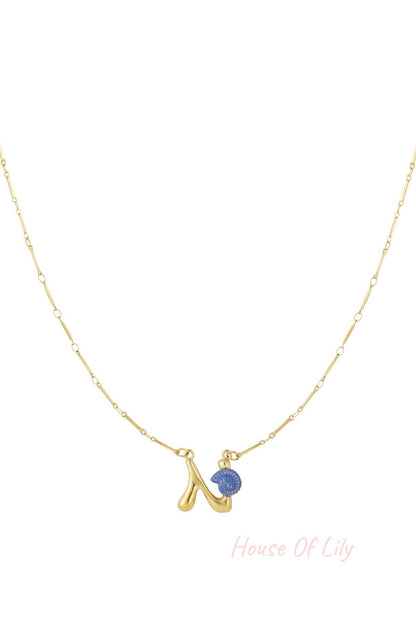 Gold chain necklace featuring a playful, puffed letter 'N' pendant accented with a small, blue spiral seashell charm.