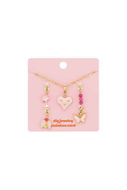 Gold chain charm bracelet set with pink enamel heart, ladybug, butterfly, flower, and beaded charms on a pink card.