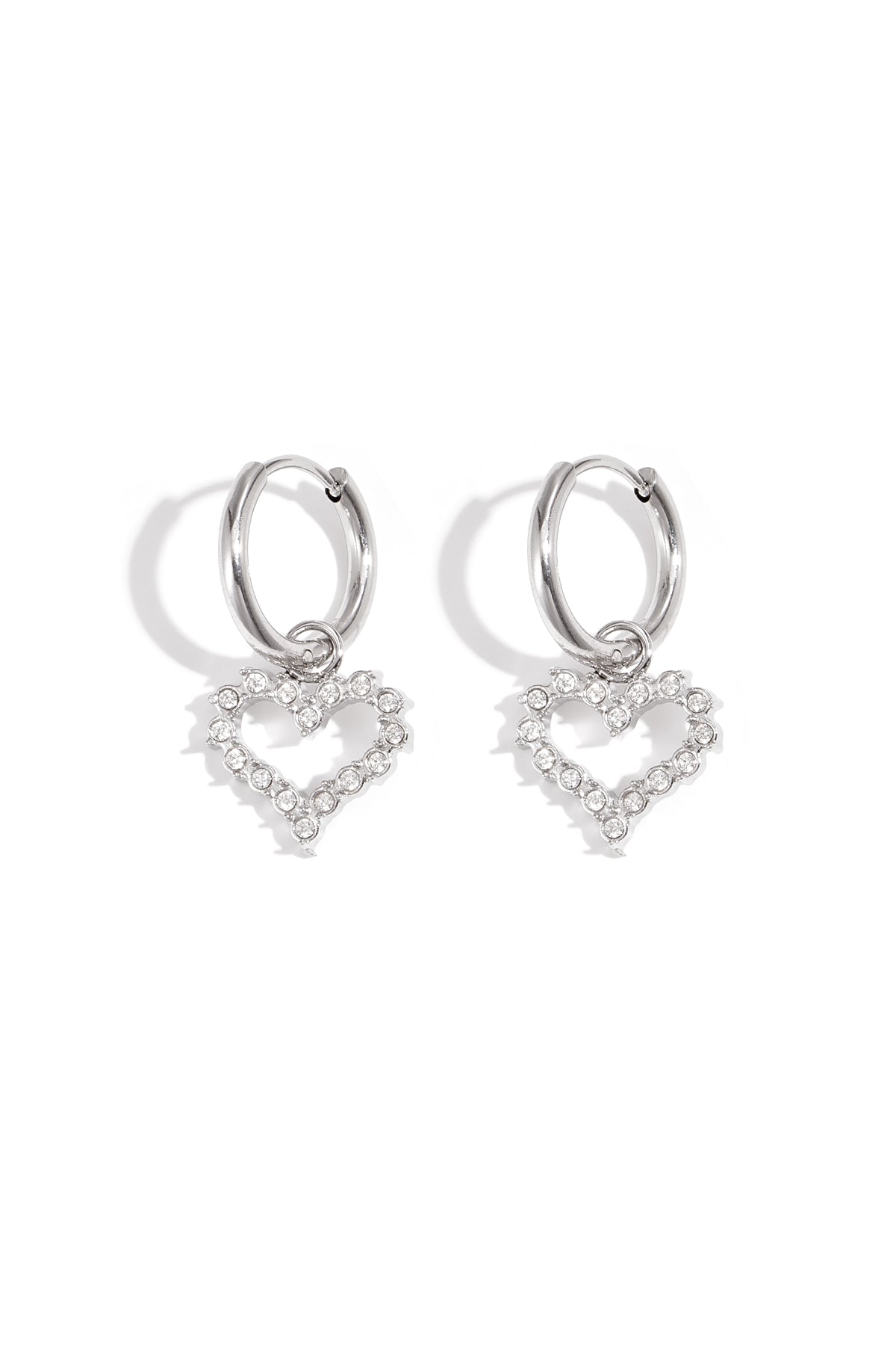 Silver-tone hoop earrings with dangling heart-shaped rhinestone charms on white background