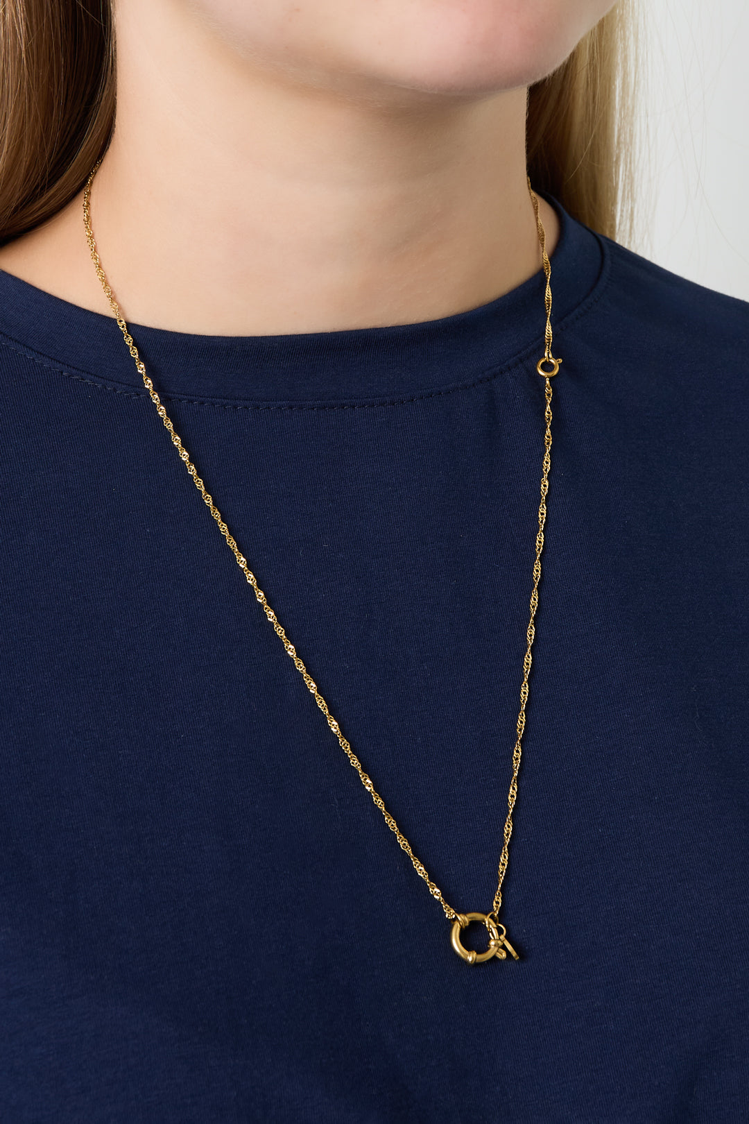 Model wearing gold chain necklace with a round spring ring clasp without charms over navy top