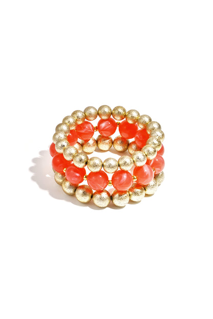 Trio of stretch bracelets featuring alternating matte gold-tone and glossy bright orange spherical beads.