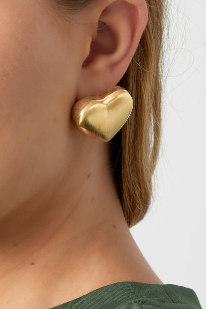 Matte gold heart stud earring worn by woman with green top showing stylish minimalist look