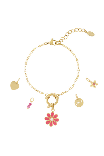 Gold charm bracelet with pink flower enamel charm, heart charm, love disc, and pink beads laid out with loose charms on white background