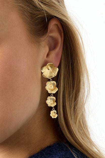 Close-up side view of model wearing gold floral cascade dangle earrings with blonde hair