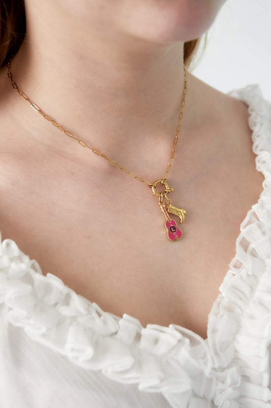 Close-up of the gold-plated charm pendant necklace worn around a woman's neck styled with a white ruffled top