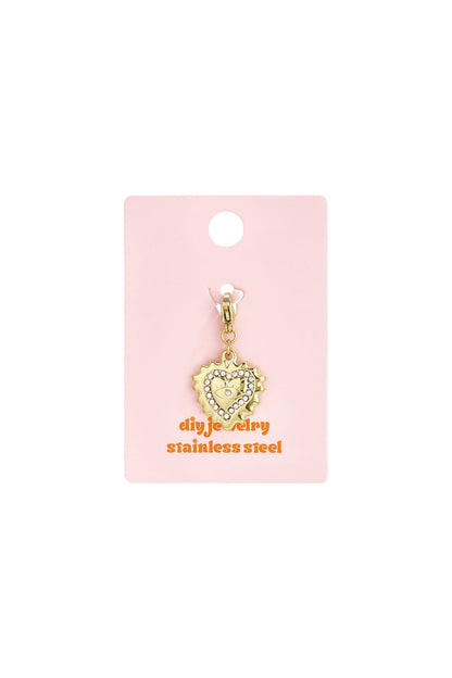 Gold stainless steel heart charm with rhinestone trim and evil eye center on a pink display card.