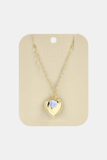 Gold chain necklace featuring a gold heart pendant with a small, light purple heart accent on a display card.