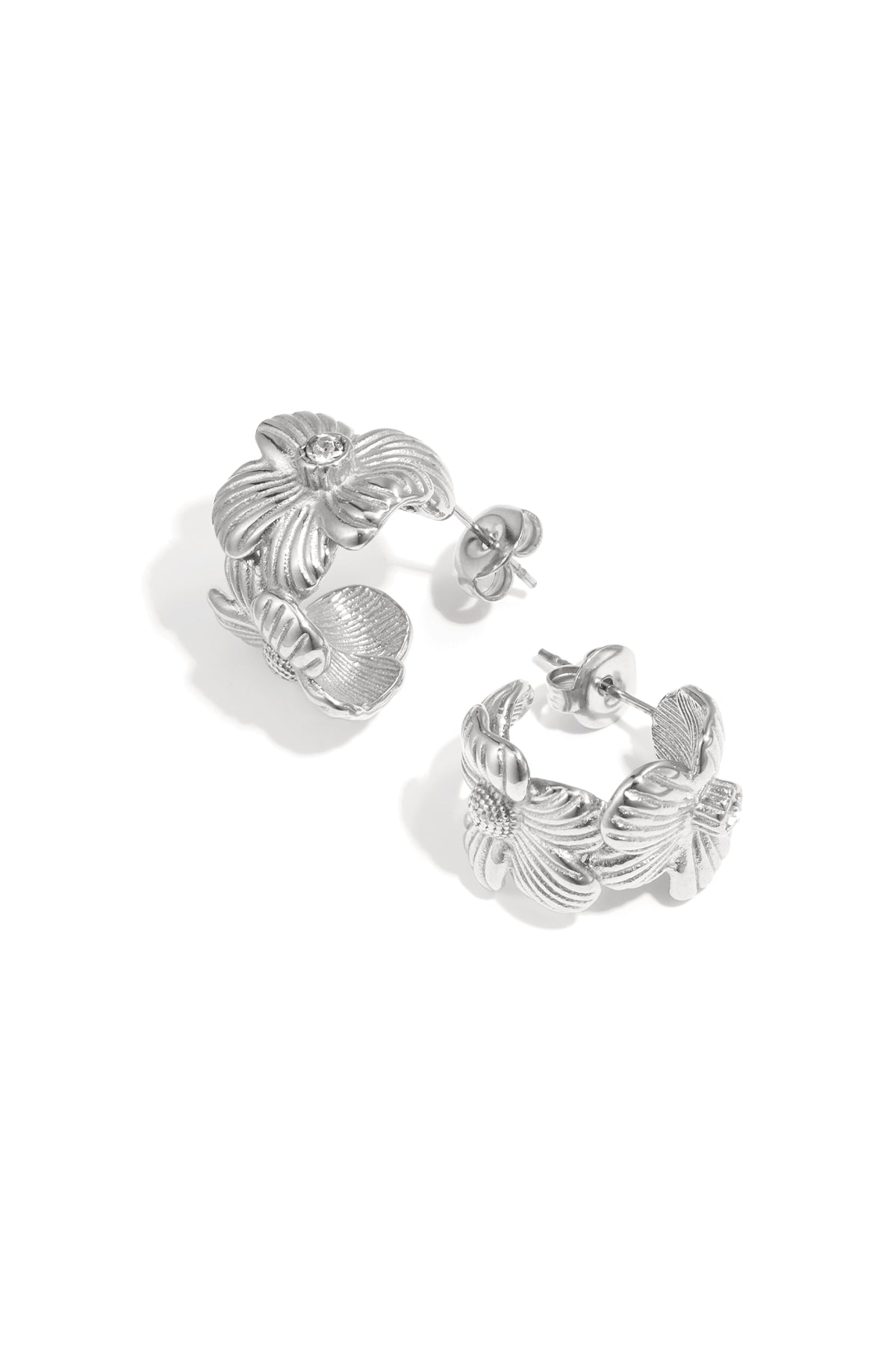 Pair of silver-tone floral hoop earrings with rhinestone center on white background