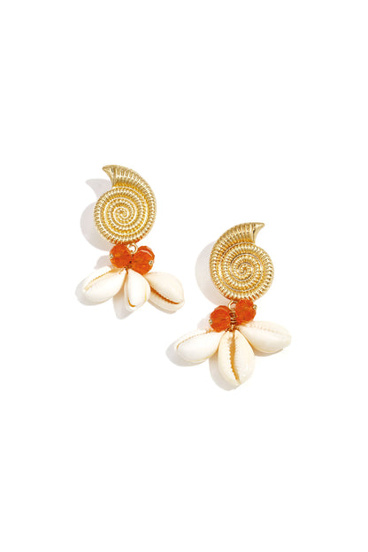 Pair of gold spiral shell earrings embellished with orange glass beads and white cowry shells against white background