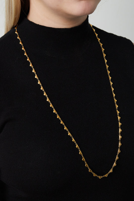Model wearing a long gold multi heart necklace paired with a black top, highlighting the necklace's length and elegant design