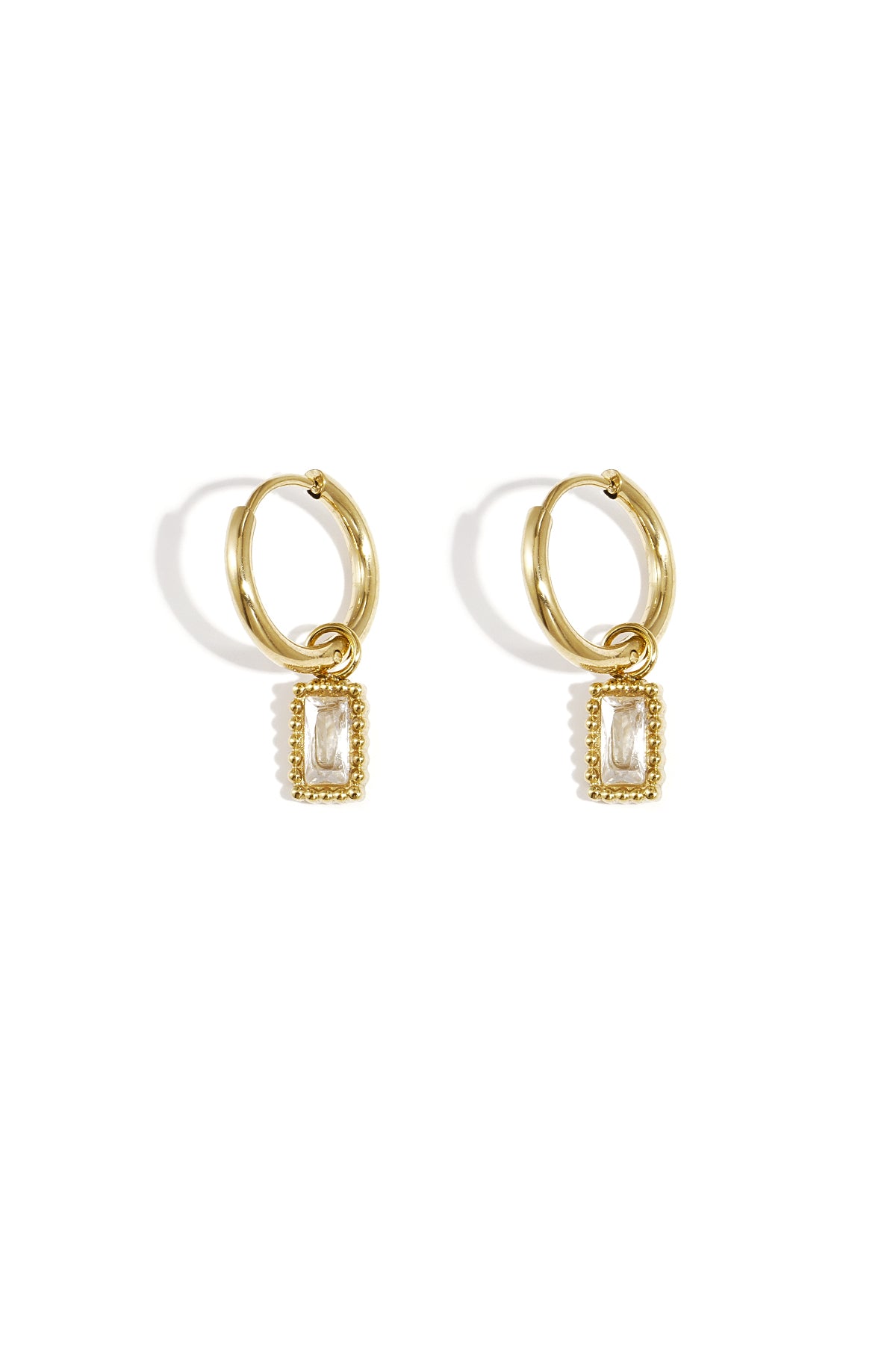 Pair of gold hoop earrings with clear rectangular gemstone charms on a white background