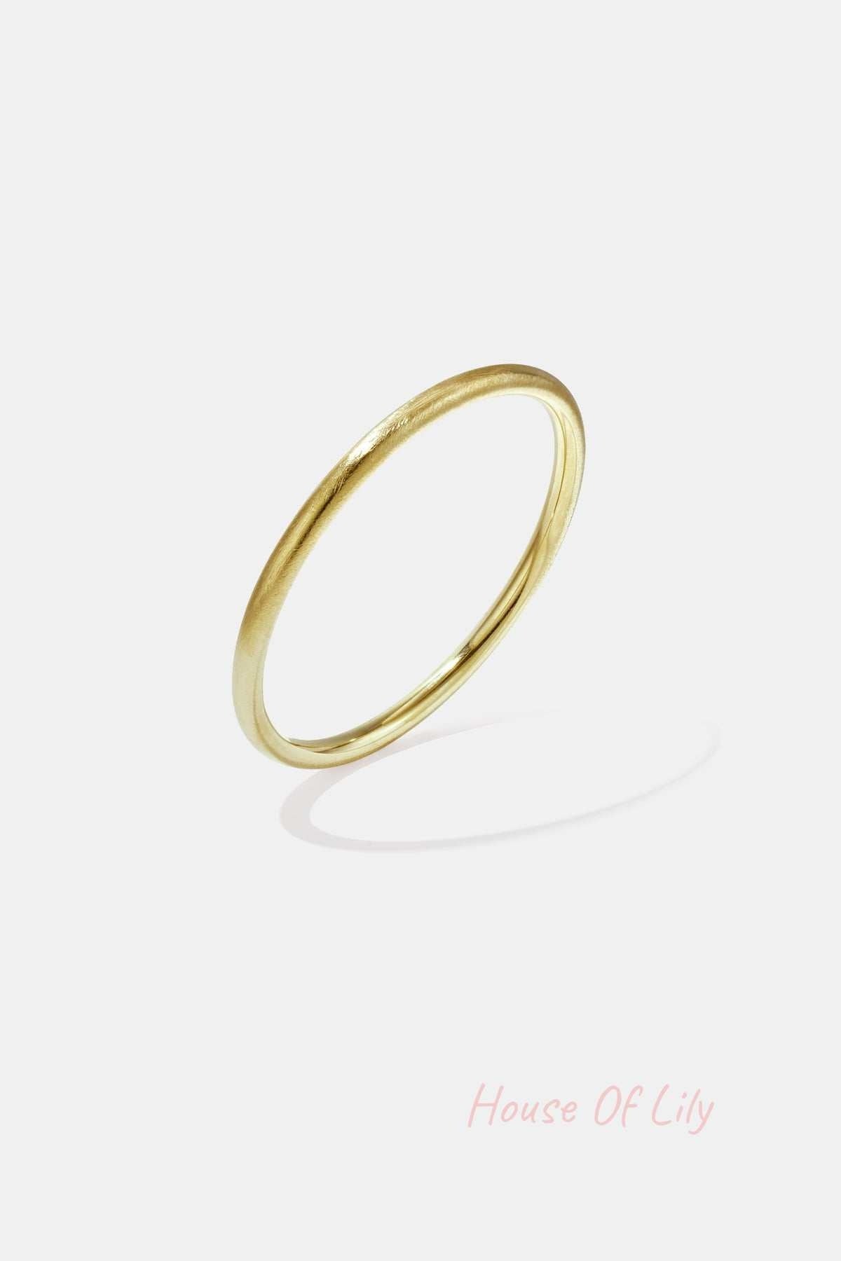 Close-up image of a sleek gold minimalist circle bangle bracelet with smooth finish on white background