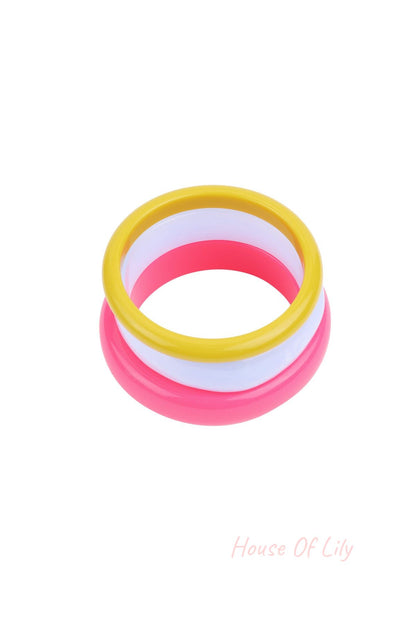 Stack of three colorful resin bangles in yellow, white, and pink on white background