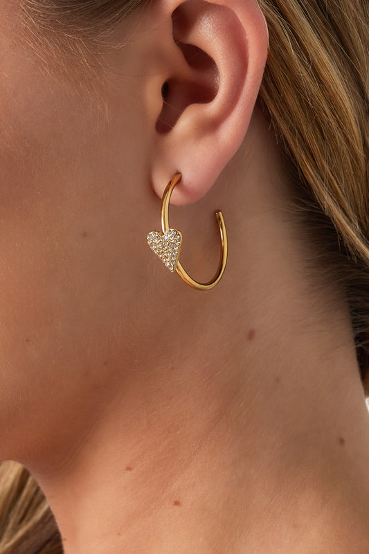 Close-up of woman wearing the gold heart hoop earrings showing size and fit