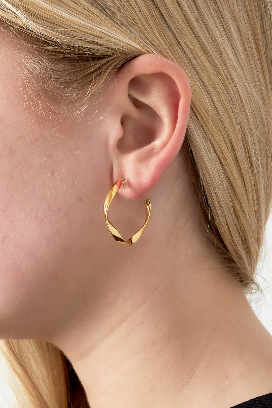 Close-up of woman wearing gold twisted square clip-on earring showing fit and style