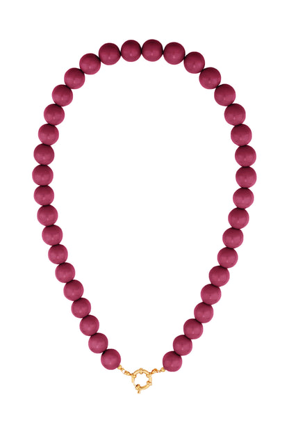 Resin beaded necklace with uniform round berry-colored beads and a gold-tone circular clasp against a white background.