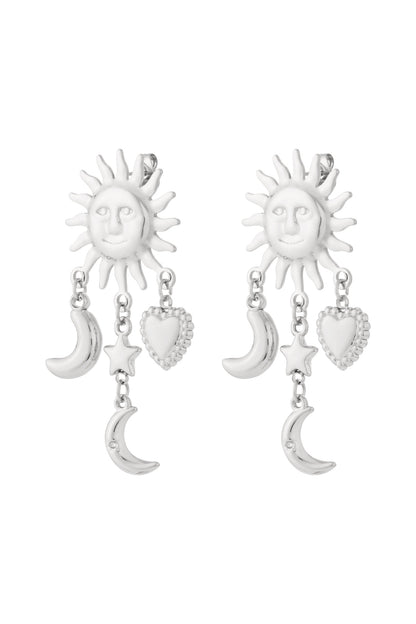 Pair of silver-tone celestial charm drop earrings featuring sun faces with dangling moon, star, and heart charms against white background