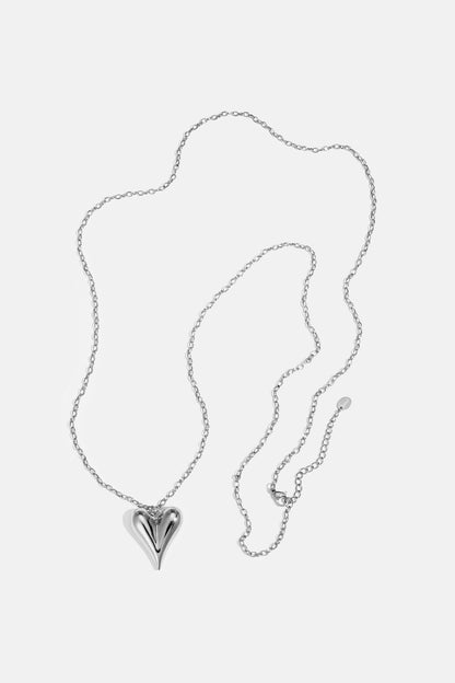 Silver heart pendant on a delicate silver chain necklace laid flat on white background
