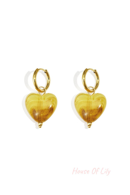 Pair of gold hoop earrings with peach glossy resin heart pendants on white background (different shade variant)