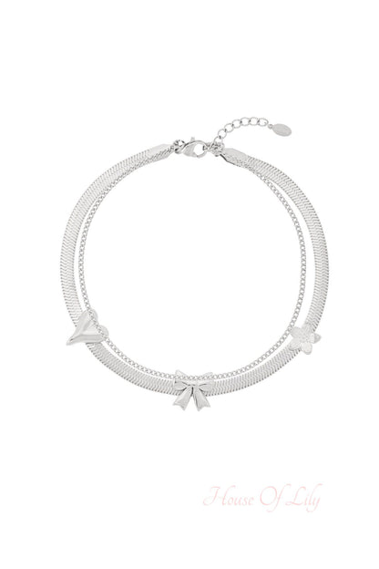 Silver double chain anklet with bow, flower, and heart charms on white background