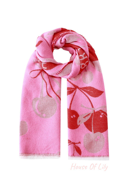 Folded pink and red cherry pattern scarf with fringed edges on white background