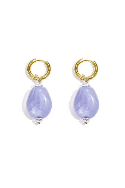 Pair of gold hoop earrings with violet cloudy resin beads on white background