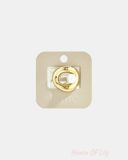 Gold organic-shaped ring with central pearl, displayed on beige card.