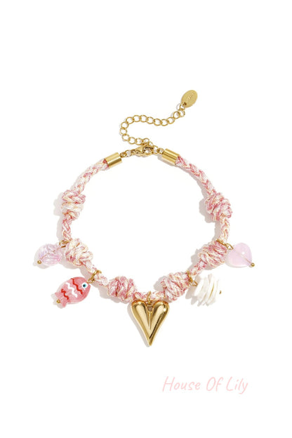 Soft pink and white twisted rope charm bracelet with gold heart and colorful charm pendants including fish and flower
