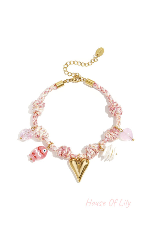 Soft pink and white twisted rope charm bracelet with gold heart and colorful charm pendants including fish and flower