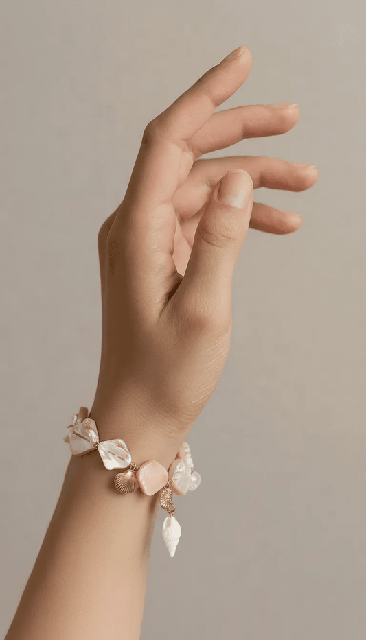 Coastal Seashell charm bracelet with iridescent shell beads and gold metal seashell accents on a delicate chain.