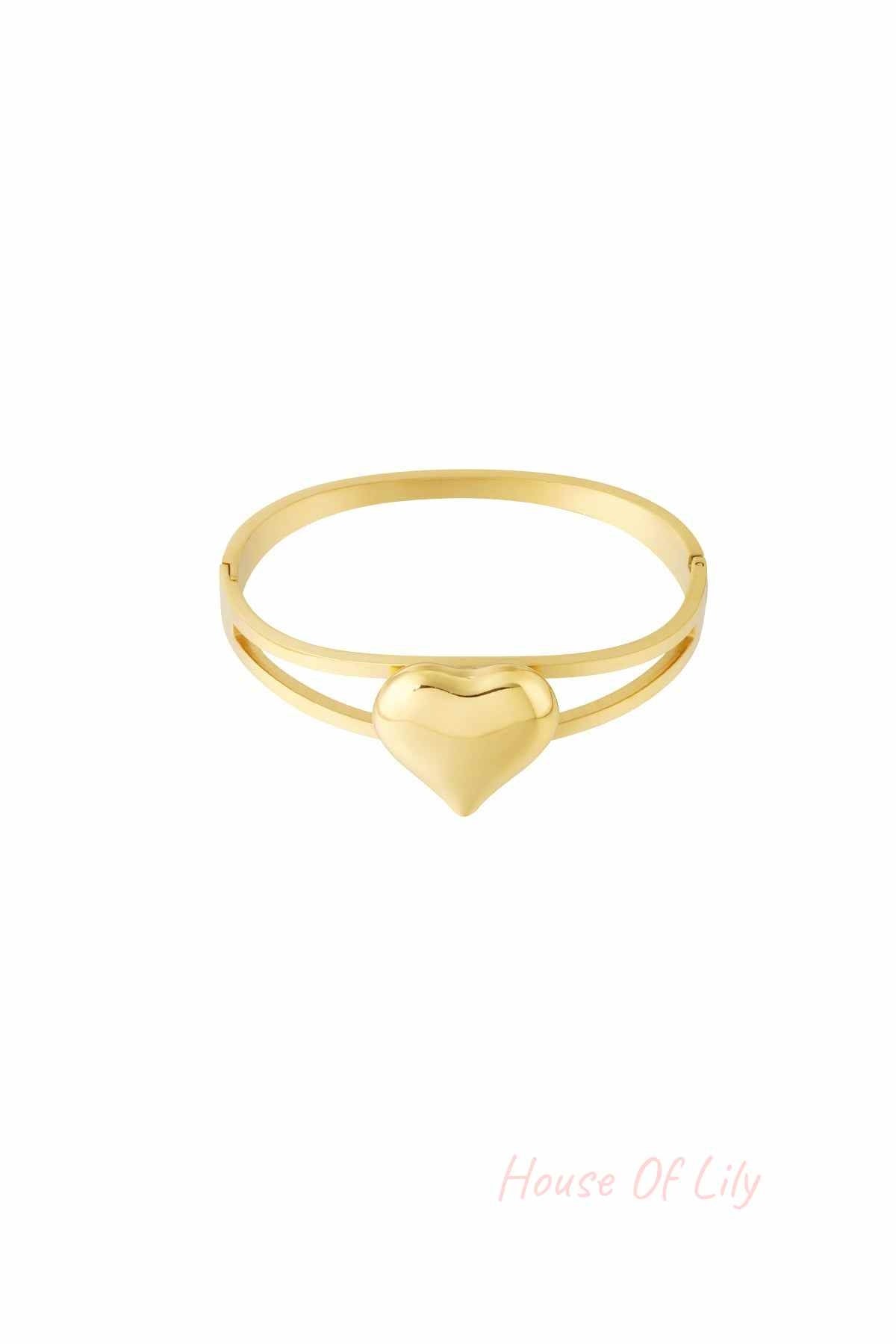 Gold bangle bracelet with a smooth heart centerpiece on a white background