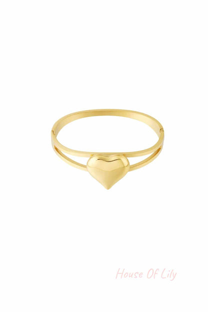 Gold bangle bracelet with a smooth heart centerpiece on a white background