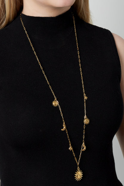 Model wearing the long celestial-themed gold necklace over a black sleeveless top