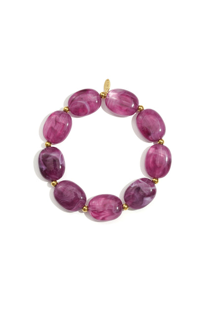 Close-up of a ruby red swirled acrylic beaded bracelet with gold spacers on white background