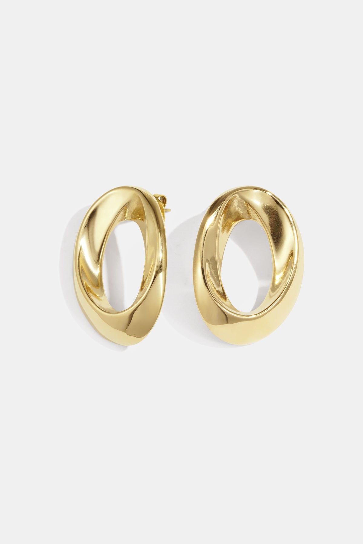 Pair of polished gold-tone twisted oval hoop earrings on white background