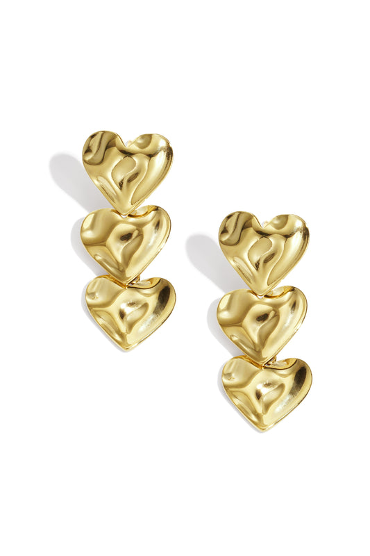 Pair of shiny gold triple heart dangle earrings with soft wave texture on a white background
