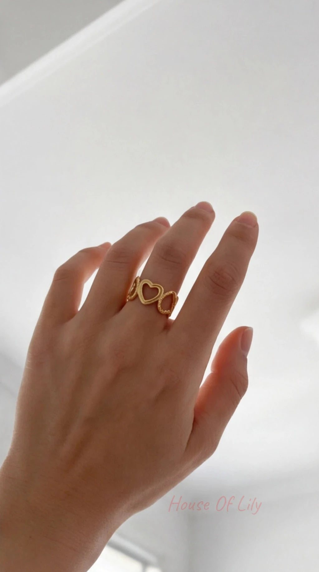 Gold Heart Link Ring worn on a finger, featuring a continuous band of interlocking open heart shapes.