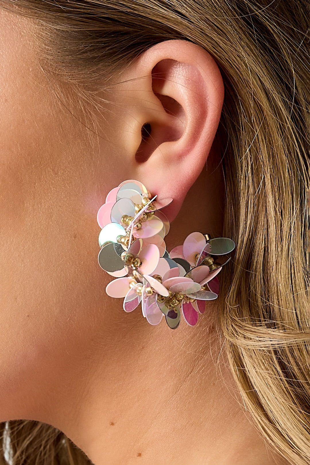Pair of sequin hoop earrings with red, orange, yellow, pink, and gold circular sequins on white background