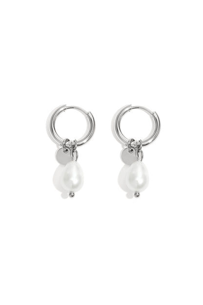 Pair of silver hoop earrings with dangling irregular-shaped white pearls and small silver discs on white background