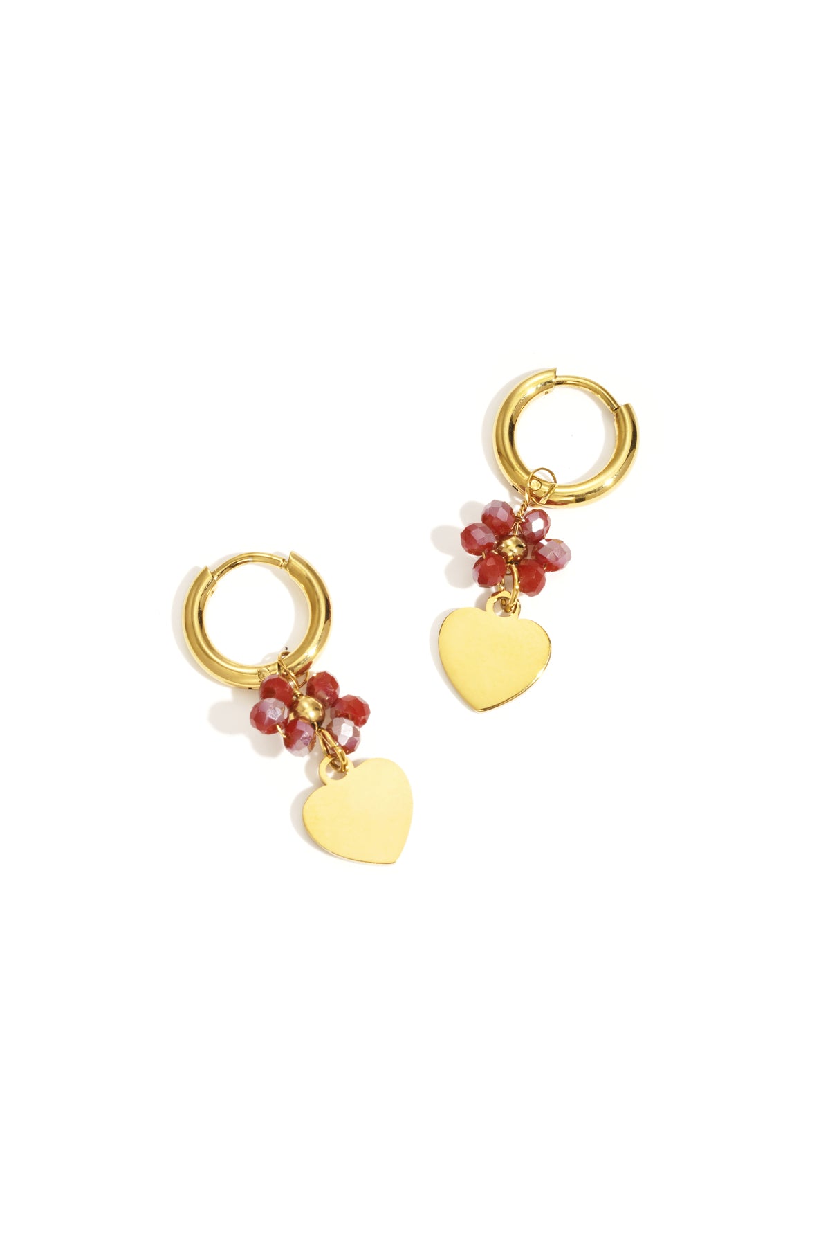 Pair of gold-tone hoop earrings with red faceted beads and dangling gold heart charms on white background