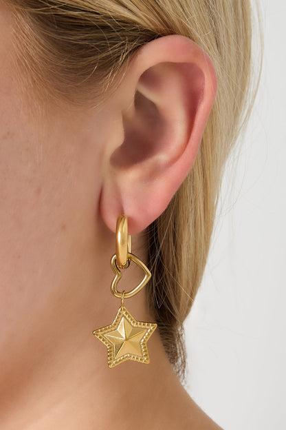 Close-up of a woman wearing gold hoop earring with heart and star charm showing soft polished finish