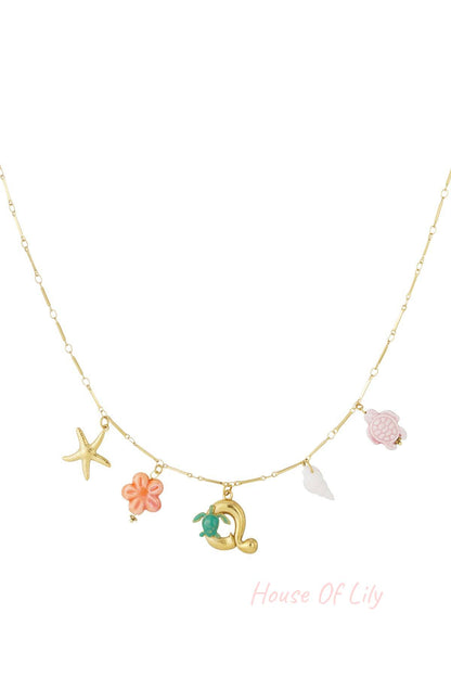 Gold chain necklace featuring a gold letter 'Q' charm with a small green turtle, alongside starfish and sea charms.