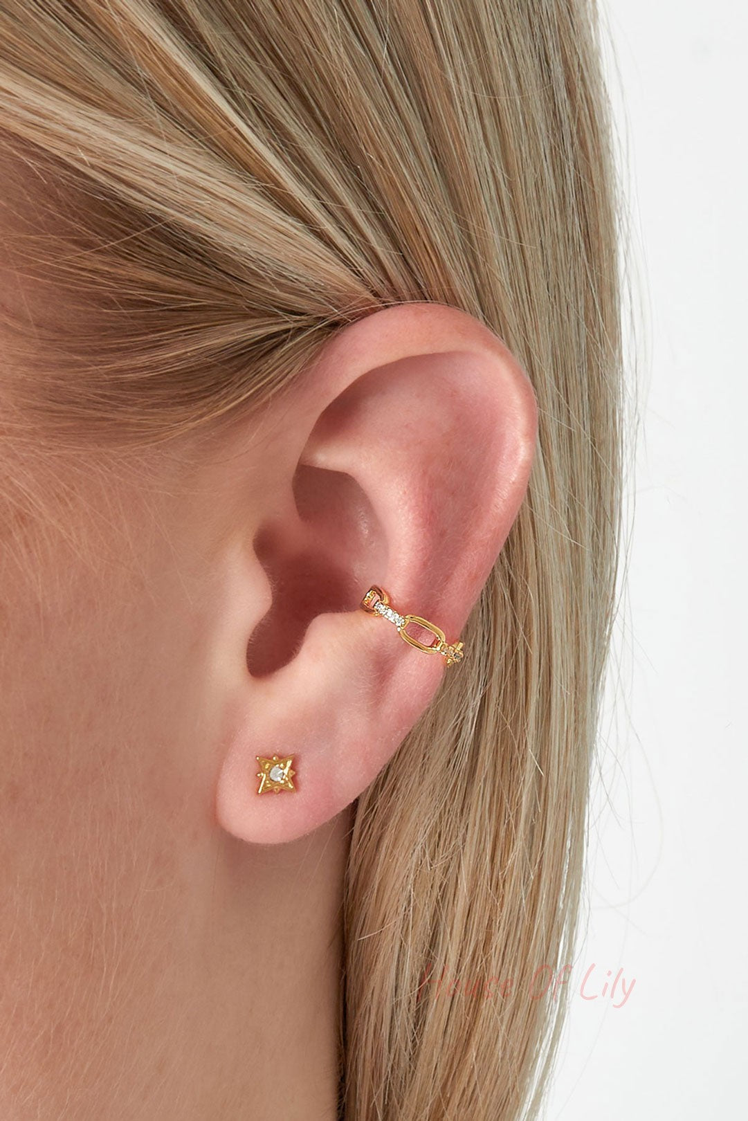 Model wearing gold chain link ear cuff on upper ear with small star stud earring in lower lobe