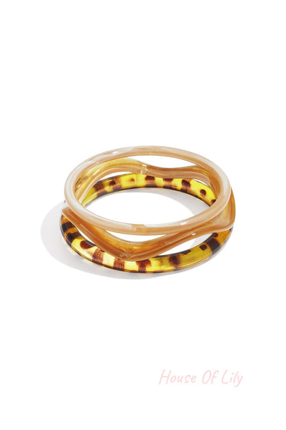 Three wavy shaped acrylic bangles in light pink, red, and purple colors on white background