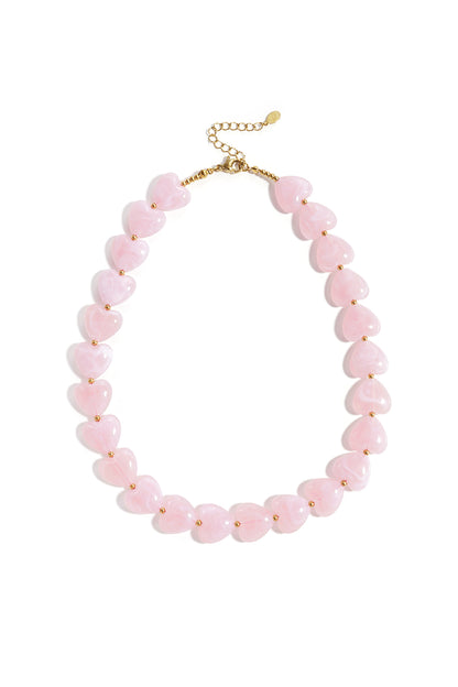 Pink heart-shaped acrylic bead necklace with gold-tone accents on white background