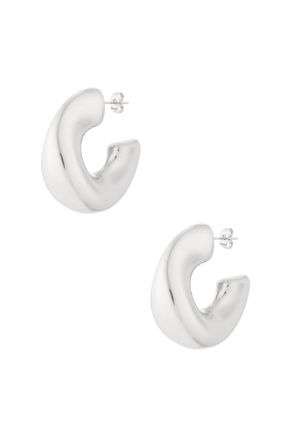 Pair of chunky sculpted hoop earrings in polished silver finish isolated on white background