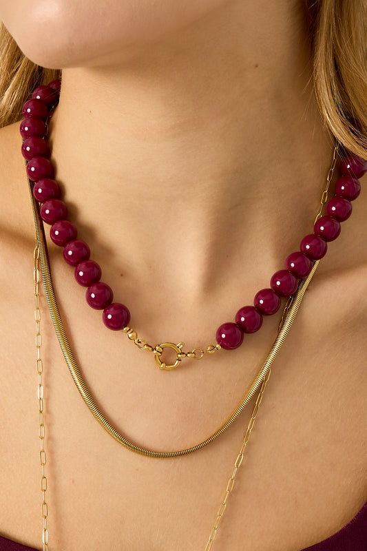 Single strand necklace with glossy lavender resin beads and gold spring ring clasp on white background