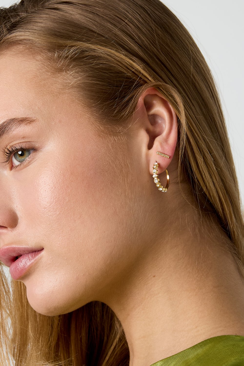 Glitch Beam gold stud earring featuring a slender, textured rectangular bar design worn on a model's ear.