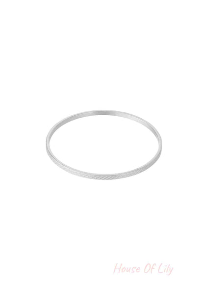 Single slim silver-tone bangle with subtle crosshatch geometric pattern on white background
